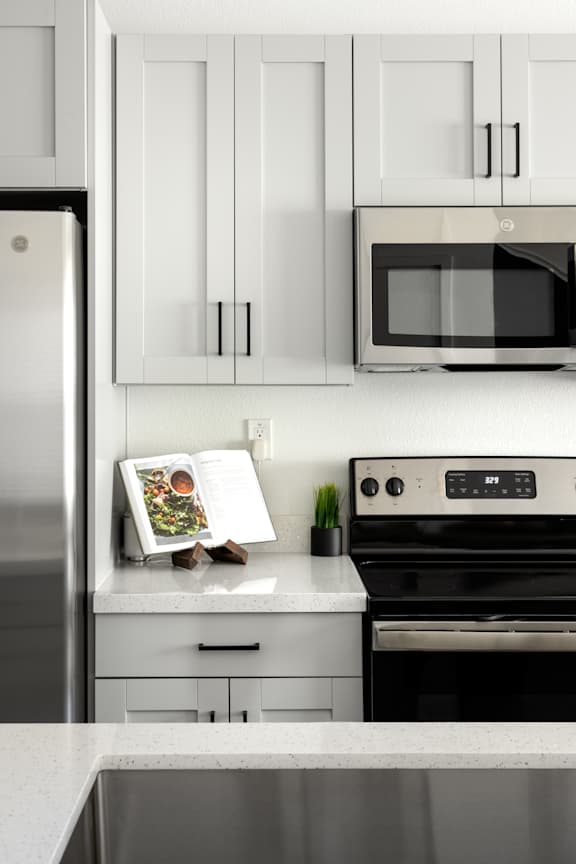 A modern kitchen with a refrigerator, microwave, oven, and cabinets.