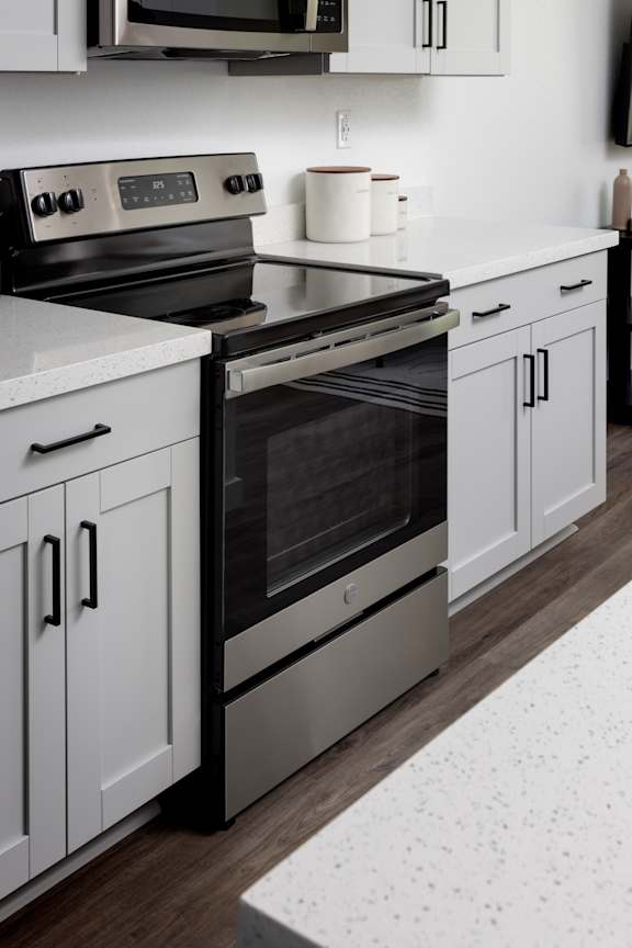 A modern kitchen with a stainless steel oven and white cabinets.