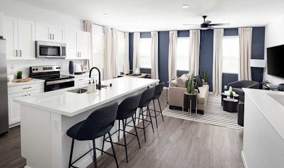 A modern kitchen with white countertops and black bar stools.