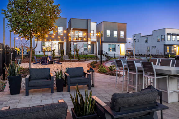 A modern outdoor seating area with black couches and tables in front of a building.