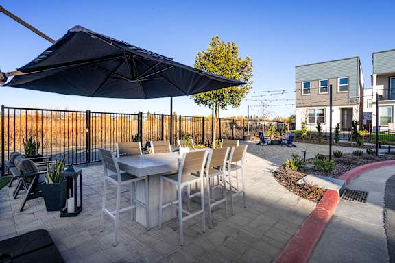 A patio with a table and chairs under an umbrella.