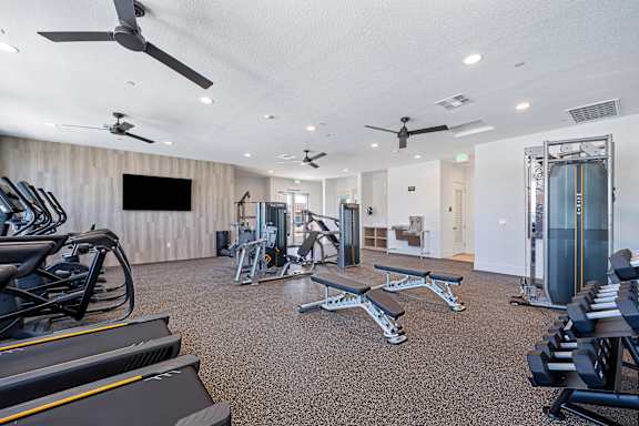 Fitness center with free weights and workout benches at Estia Roseville Apartments, Roseville, California