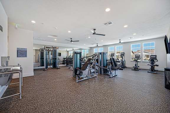 A spacious gym with a variety of equipment and a ceiling fan.