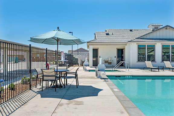 Poolside patio with umbrella table and lounge seating at Estia Roseville Apartments, Roseville, 95747