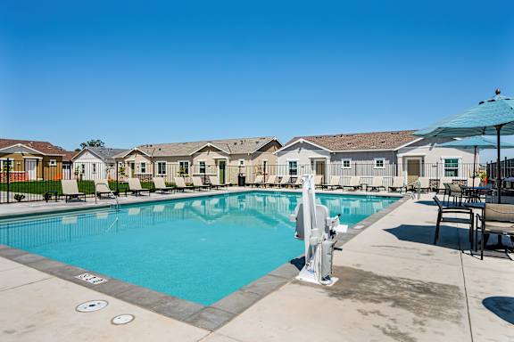 Pool deck with lounge seating and patio umbrellas at Estia Roseville Apartments, Roseville, California