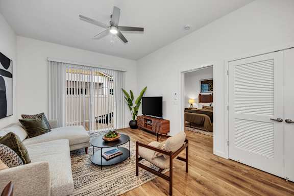 A living room with a white couch, a coffee table, and a ceiling fan.