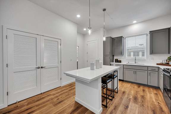 A modern kitchen with a white island and wooden floors.