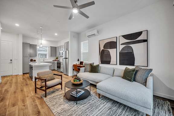 A living room with a grey couch, a coffee table, and a ceiling fan.