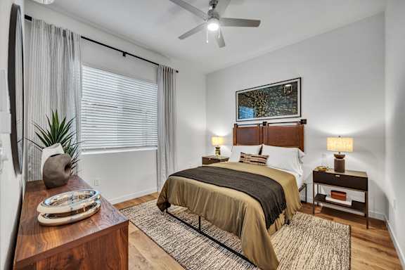 A bedroom with a bed, nightstand, and a ceiling fan.