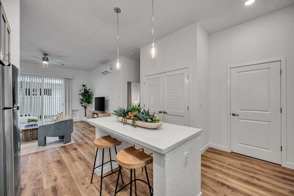 A kitchen with a white counter and bar stools.