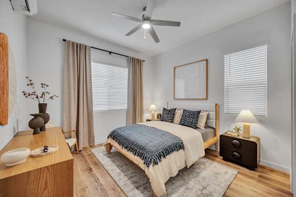 A bedroom with a bed, nightstand, and a ceiling fan.