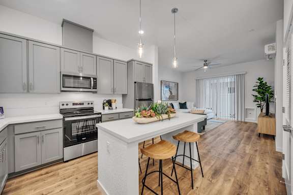 A kitchen with a white island and wooden bar stools.