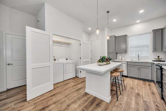 A kitchen with a white island and wooden floors.