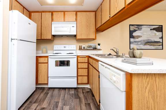 A kitchen with wooden cabinets and white appliances at 55+ FountainGlen Goldenwest Senior Apartments, Westminster