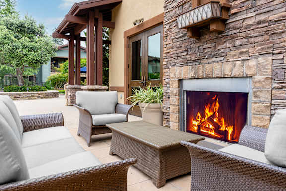 A patio with a fireplace and chairs at 55+ FountainGlen  Jacaranda, California, 92833