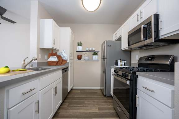 A kitchen with white cabinets and black appliances at 55+ FountainGlen Laguna Niguel, Laguna Niguel
