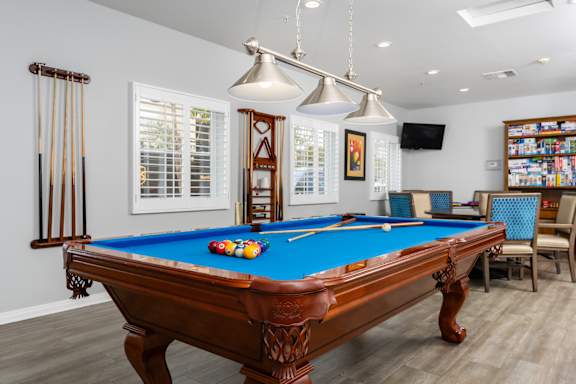 A pool table with a blue cloth and a few balls on it at 55+ FountainGlen Seacliff, Huntington Beach, CA, 92648
