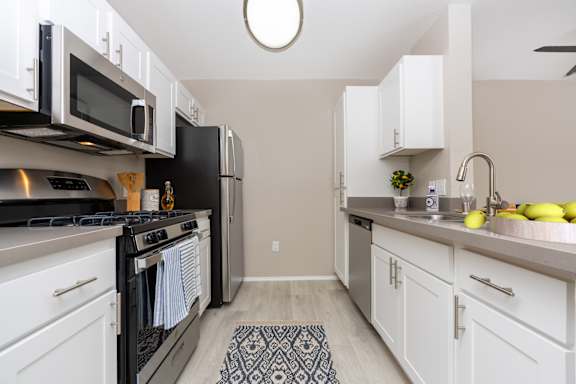 A kitchen with white cabinets and black appliances at 55+ FountainGlen Seacliff, Huntington Beach, CA, 92648