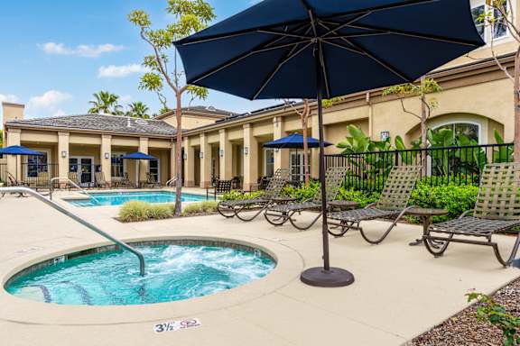 A pool with a blue umbrella and chairs around itat 55+ FountainGlen Seacliff, Huntington Beach, CA, 92648