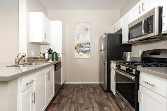 A kitchen with white cabinets and black appliances at 55+ FountainGlen Valencia, Valencia, California