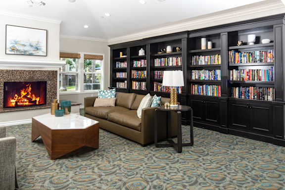 A living room with a fireplace, a couch, a coffee table, and a bookshelf. at 55+ FountainGlen Grand Isle, California