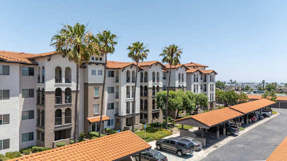 A row of apartment buildings with a parking lot in front. at 55+ FountainGlen Terra Vista, Rancho Cucamonga, California