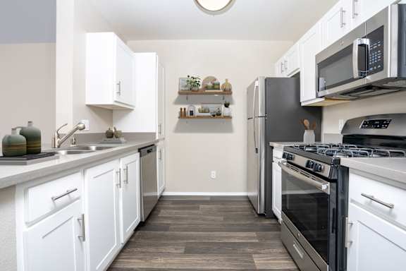 A kitchen with white cabinets and black appliances. at 55+ FountainGlen Terra Vista, Rancho Cucamonga, CA