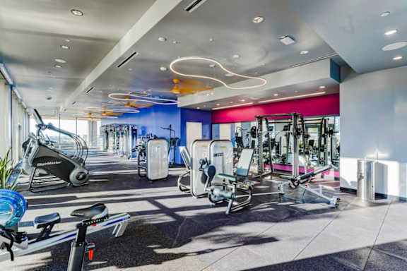A gym with a variety of equipment including treadmills, stationary bikes, and weight machines.