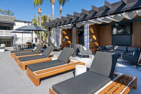 A patio with wooden furniture and a black umbrella at Verandas Apartments, West Covina, 91791