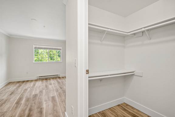 A room with white walls and wooden flooring with a window. at Lakemont Orchard Apartments, Issaquah , Washington