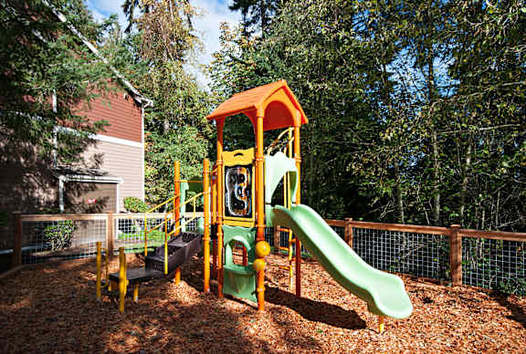 A playground with a green slide and a yellow and orange play structure. at Lakemont Orchard Apartments, Issaquah , Washington