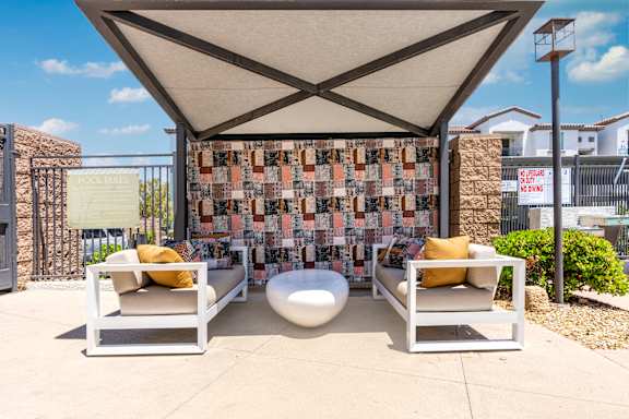 A patio with two chairs and a table under a canopy at Miro at the Parc Apartments, Henderson , Nevada