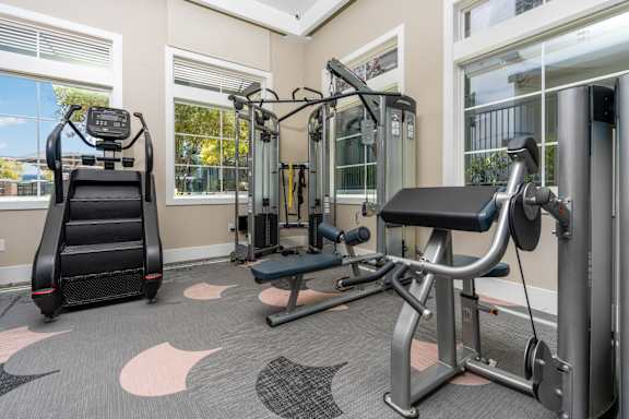 A gym with a treadmill, a bench press, and a squat rack at Miro at the Parc Apartments, Henderson , NV