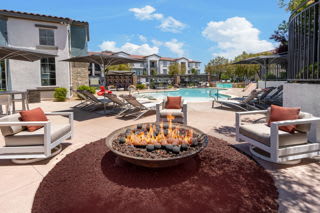 A fire pit sits in the middle of a patio with chairs around it.