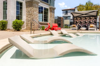 A modern pool with a red chair and a stone building in the background.