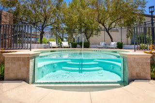 A small pool with a glass wall in the middle of a patio.