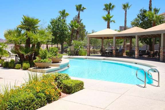A pool surrounded by palm trees and a patio area at Avalon at Seven Hills Apartments, Nevada, 91790