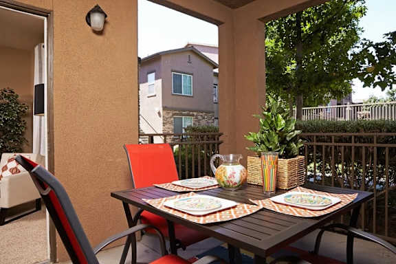 A table set for a meal on a patio with a view of apartment buildings.