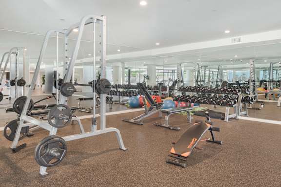A gym with a variety of equipment including weights and exercise balls at Wilshire Valencia Apartment, Los Angeles, CA, 90017