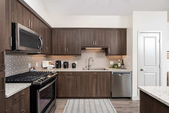 A kitchen with a black stove top oven and a black and white tiled backsplash.