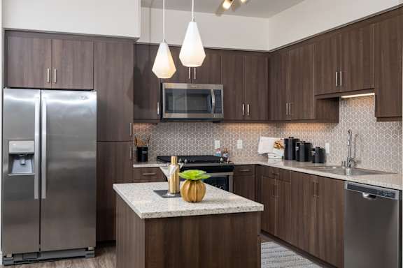 A kitchen with a refrigerator, microwave, and a counter with a pumpkin on it.