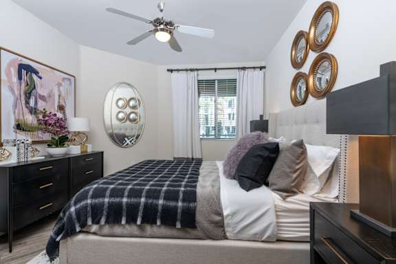 A bedroom with a bed, dresser, and a ceiling fan.