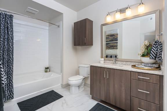 A bathroom with a white toilet, a white bathtub, a sink, and a mirror.