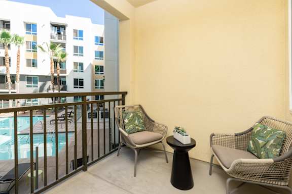 A balcony with two chairs and a table with a plant on it.