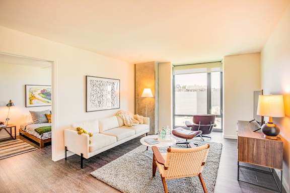 A well-lit, modern living room with a white sofa and a wooden chair.at The Rise, San Francisco