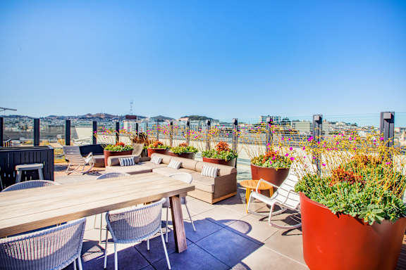 A patio with a table, chairs, and potted plants.at The Rise, San Francisco, CA 94103