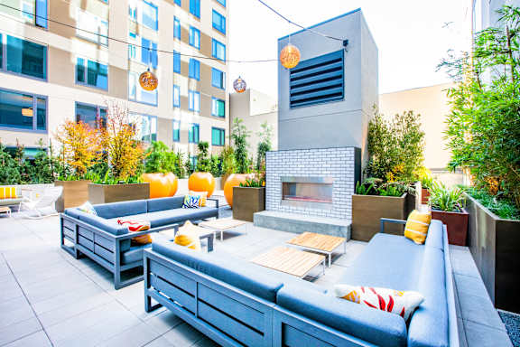 A modern outdoor seating area with blue couches and a fireplace.at The Rise, San Francisco, CA
