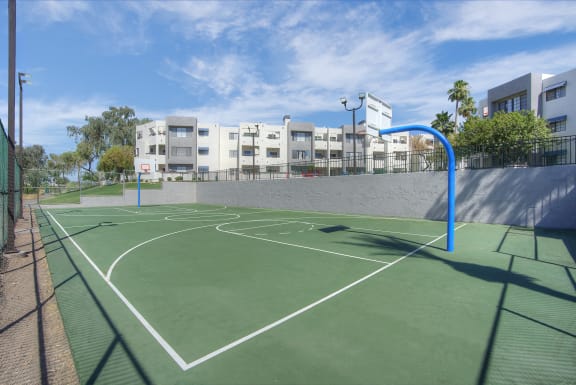 a green basketball court with buildings in the background at Vaseo Apartments, Arizona
