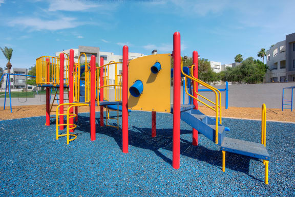 a playground with a yellow and red structure in a park at Vaseo Apartments, Arizona, 85022