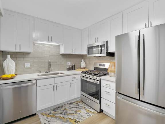 A modern kitchen with white cabinets and stainless steel appliances at Verandas Apartments, West Covina, California